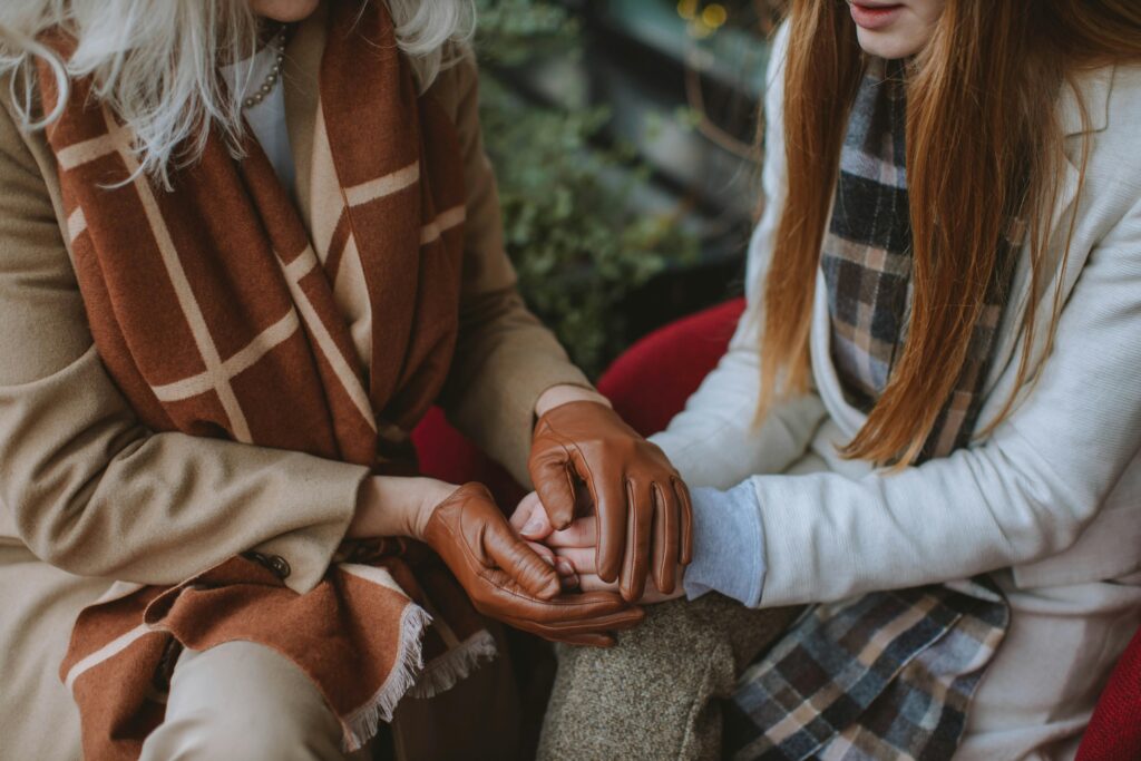 A close-up of two women sharing a tender moment, holding hands in warmth and connection.